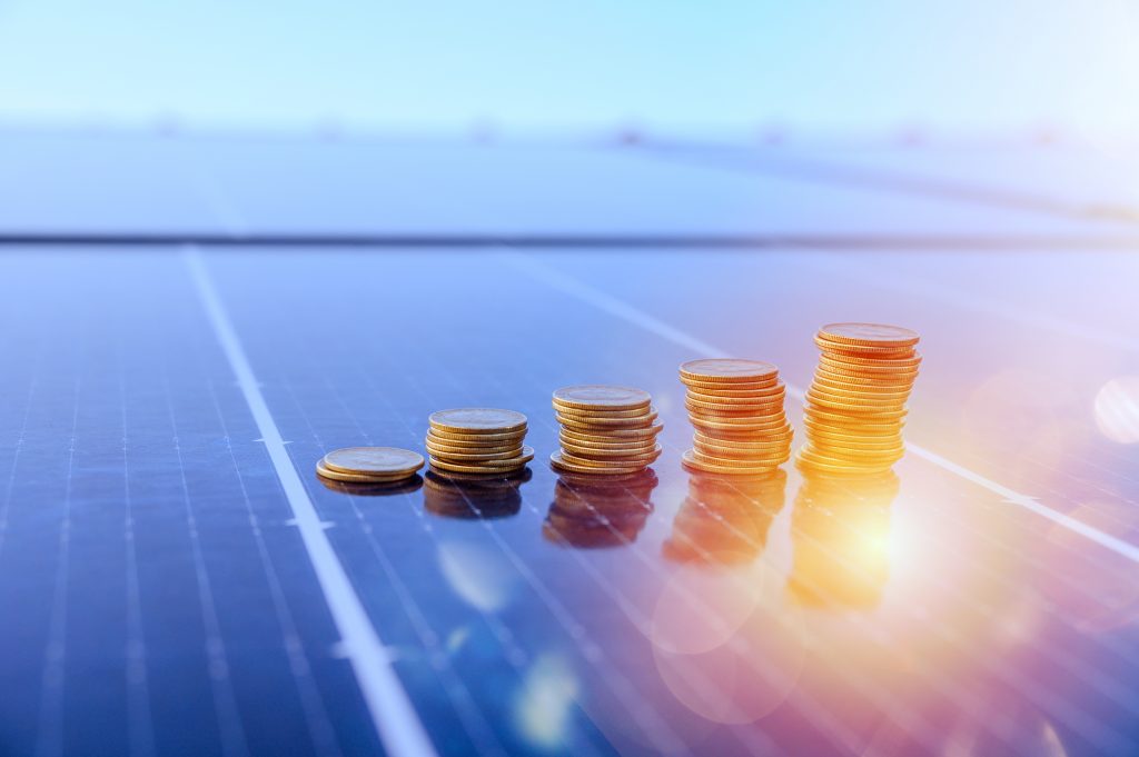 Geldmünzen auf Photovoltaik. Geld verdienen mit der Einspeisevergütung.