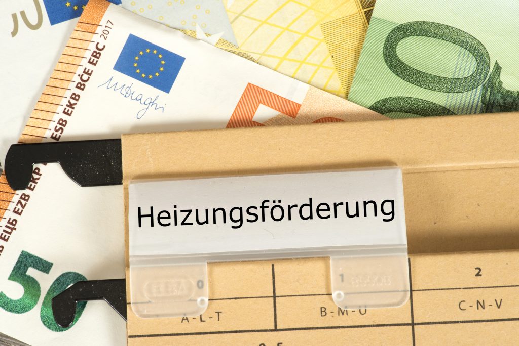 Förderung Heizung. Antrag auf Heizungsförderung vor Geldscheinen.