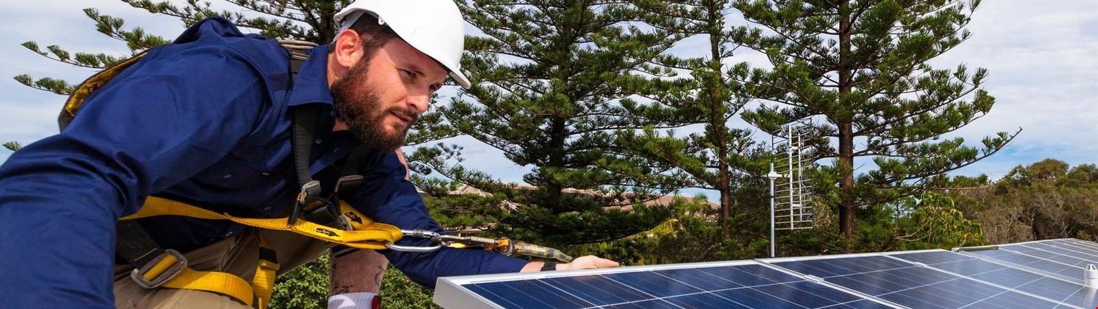 Ein Solarteur installiert eine Photovoltaikanlage.