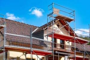 Heller Altbau mit einem Baugerüst davor vor blauem Himmel.